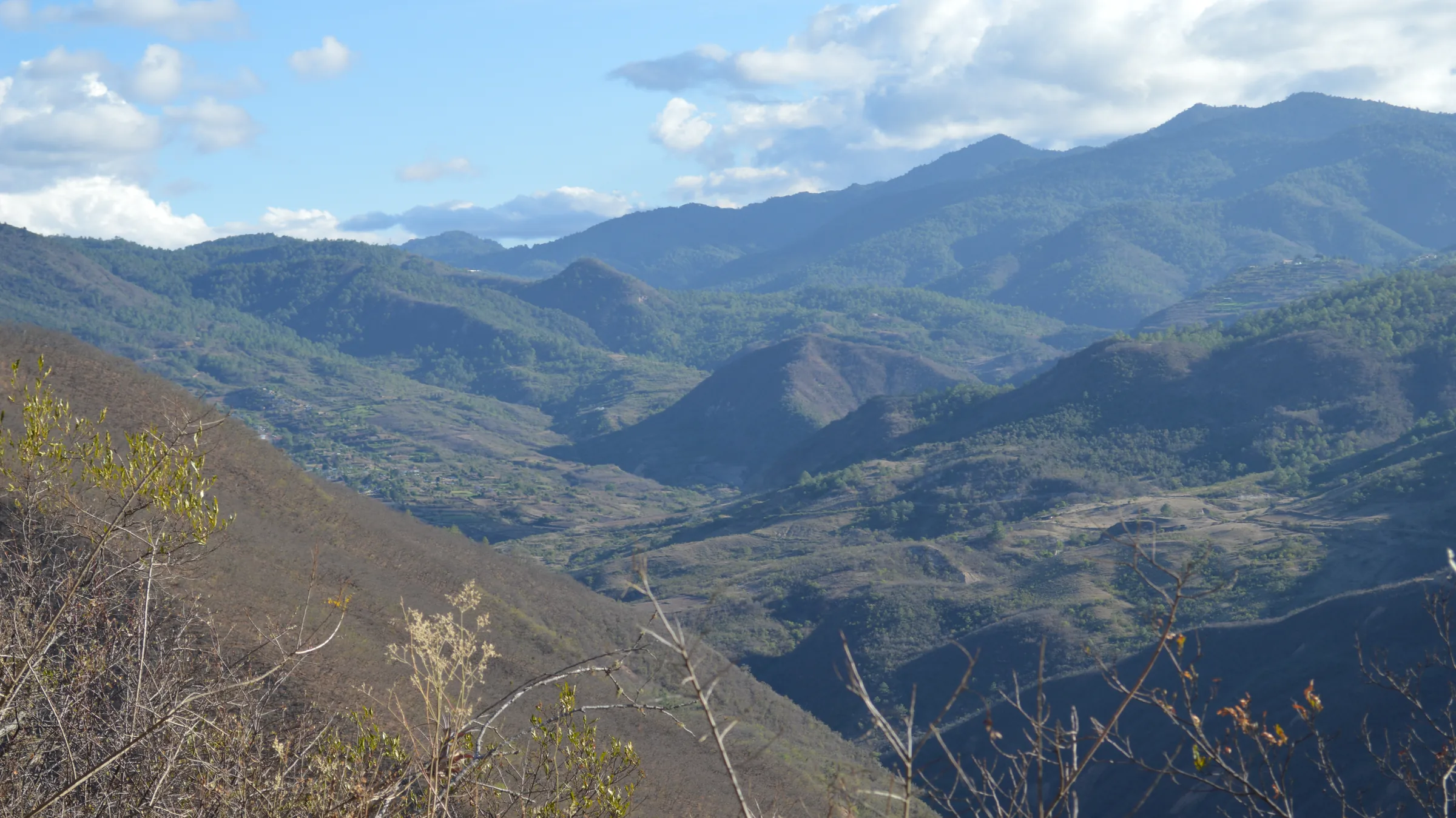 Montañas de Oaxaca vistas desde la carretera federal 175: cumbres boscosas una detrás de otra, un valle con parcelas y casas dispersas en el fondo y nubes bajas sobre la línea de cerros.